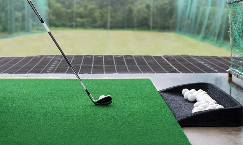 Golfschläger und Bälle auf einer Golf Abschlagmatte